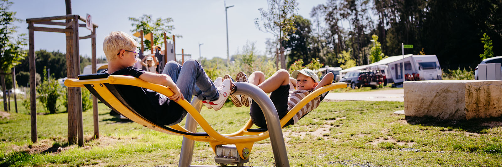 Children recline on a seesaw and play at a playground.